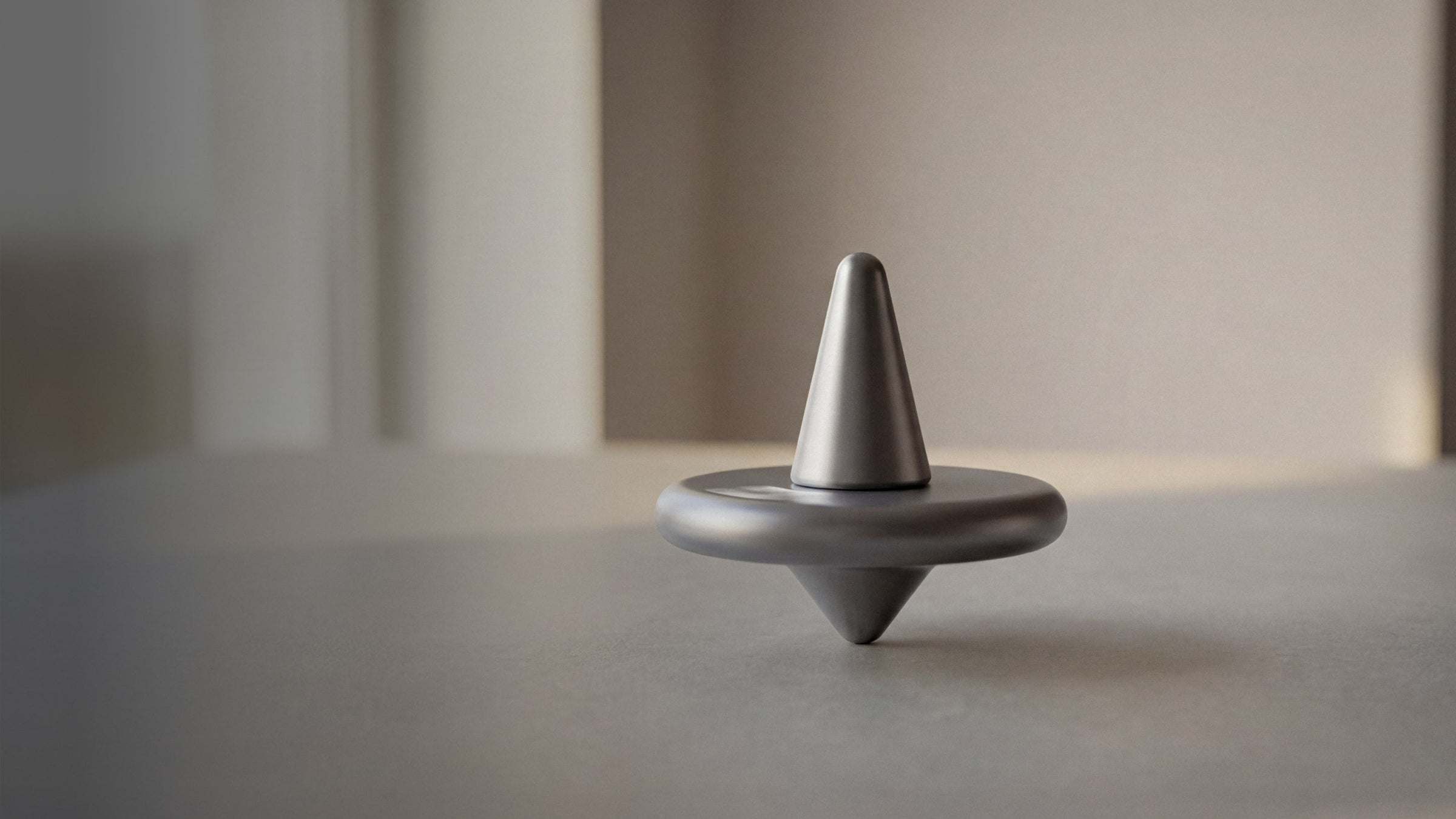 Amsterdam Dynamics ST-01 spinning top hero image showing product in a minimal desk setting
